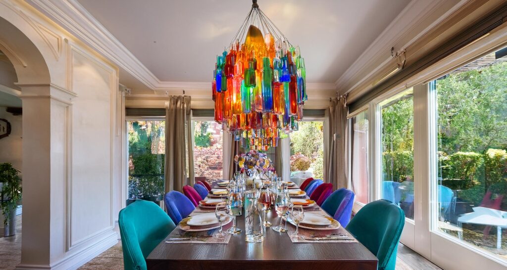 Murano glass chandelier with a mix of colorful glass pieces suspended above a formal dining table, enhancing the luxury dining experience